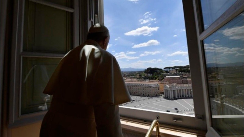 El Papa Francisco junto a una ventana abierta del Vaticano, mira a la Plaza de San Pedro.